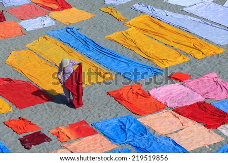 AGRA,INDIA - 25/03/2013 : Laundry service in Yamuna riverside in Agra city ,India.Laundries spread out on the sand of riverside to dry.Unidentified laundrywoman collecting laundries  after they dry.