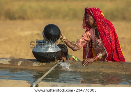 PUSHKAR,INDIA - November 3,2014 : Unidentified women draw water form the well and take it to her tent in desert near Pushkar,India