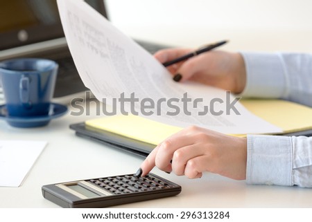 Young professional woman works on financial  reports of a company by using technological tools and equipments.She evaluates the performance and success of the management of divisions in a company.