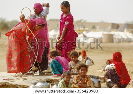 Jaisalmer, India - November 9, 2014 : Unidentified women and children draw water from the draw well and carry the pots to their village near Thar desert, Jaisalmer, Rajasthan, India
