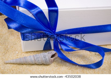 photo of gift box and shell on the sand