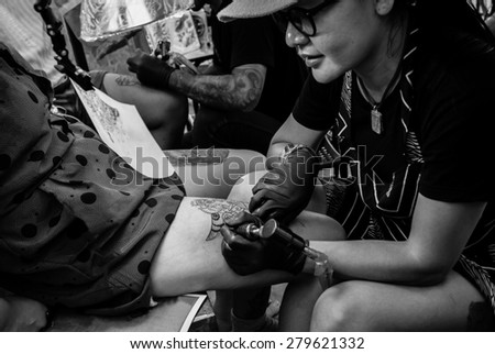 Showing process of making a tattoo. woman tattoo artist