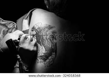 Showing processing of making a tattoo by woman artist. Tattoo design in pattern,koi tattoo : Tattoos art on human body skin : Tattooist machine,gun: Free space to fill,text