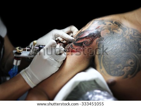 Showing processing of making a tattoo by woman artist. Tattoo design in  pattern,Buddha face tattoo : Tattoos art on human body skin black and white  tone : Tattooist machine,gun. - Stock Image -