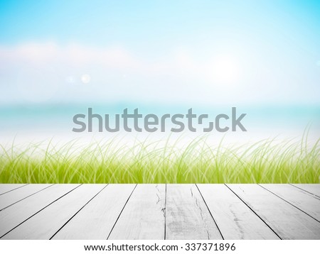 White old wood floor with abstract blurred on vacation summer ocean beach background . Blue water and sky bright. ocean beach with green grass.