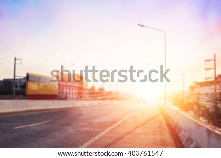 Soft focus expressway asphalt road with car in a city landscape at sunrise. Driving on a Highway with colorful sky. Blurred of peaceful landscape sunset. Abstract blur glowing bokeh colorful.