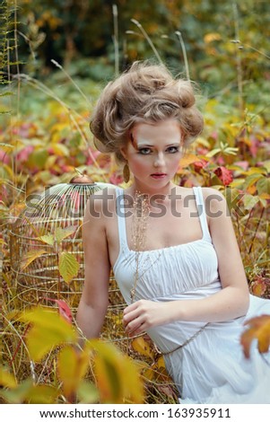 Beautiful fairy girl with golden cage in a forest