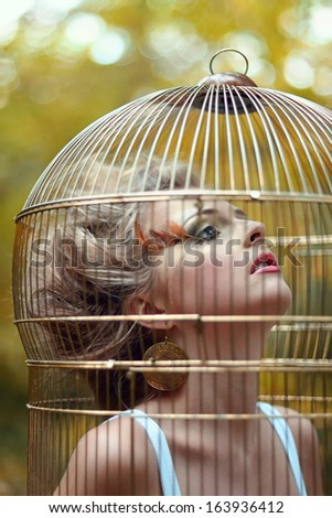 Beautiful blonde girl in a golden cage