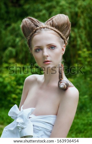 Naked young woman with fashion hairstyle and big snail on her shoulder