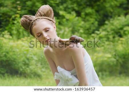 Naked yong woman with fashion hairstyle and big snail on her shoulder