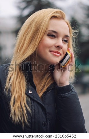 Charming blonde girl smiles and talks on mobile telephone