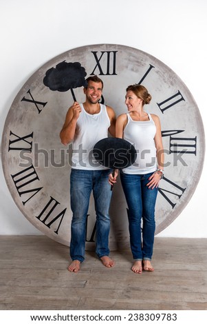 Happy Pregnant Couple dressed in white showing sign speech bubble banners looking happy excited and having idea on white background with giant clock