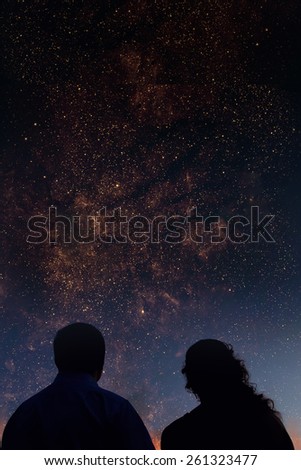 Silhouettes of couple looking at stars. Starry night sky with colorful galaxies, astronomical background with place for your text.Elements of this image furnished by NASA.