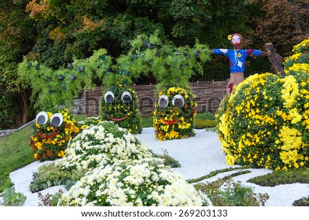 Vegetable garden, guarded by a scarecrow. Big figures made from flowers in the shape of vegetables with colorful chrysanthemums. Parkland in Kiev, Ukraine