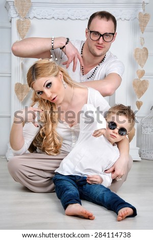 A happy stylish family with a child in white living room showing cool hand gesture