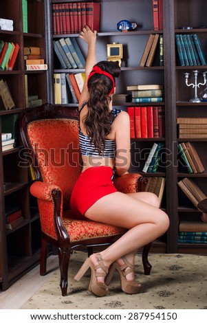 Pinup girl takes a book from the bookshelf