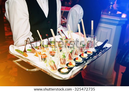 Server holding a tray of appetizers at a banquet. Toned image instagram style