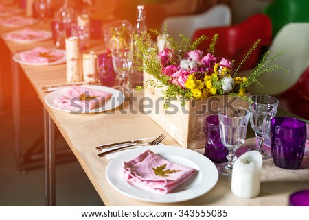 Decorated table ready for dinner. Beautifully decorated table set with flowers, candles, plates and serviettes for wedding or another event in the restaurant
