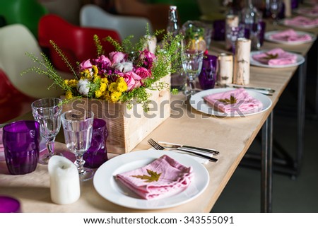 Decorated table ready for dinner. Beautifully decorated table set with flowers, candles, plates and serviettes for wedding or another event in the restaurant
