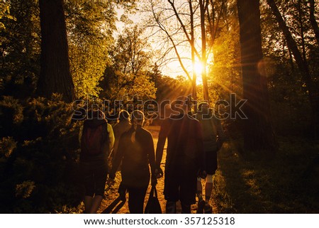 Group of friends walking with backpacks in sunset from back. Adventure, travel, tourism, hike and people friendship concept