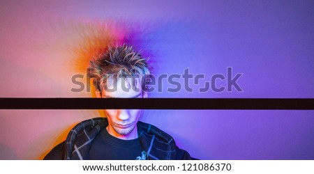 Colorful concept photograph of a young male hiding his eyes with a black stick. Colorful background.
