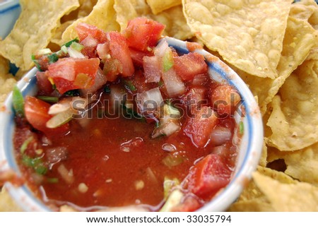 Corn chips around a bowl of red chunky salsa