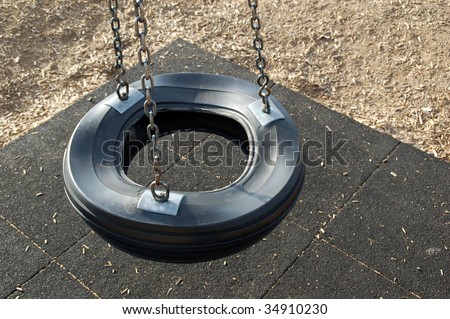 An empty tire swing on a sunny day in a playground.