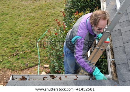 Man cleaning gutters on ladder