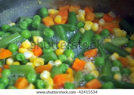 Vegetables boiling in steaming hot water in a pan.