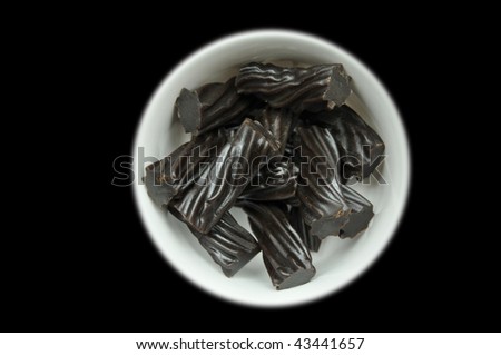 Black Australian Licorice in white bowl isolated on black background