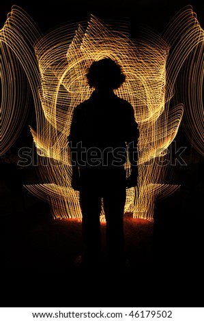 Silhouette of anonymous man standing in front of golden glowing lines. Everything else in the picture is black
