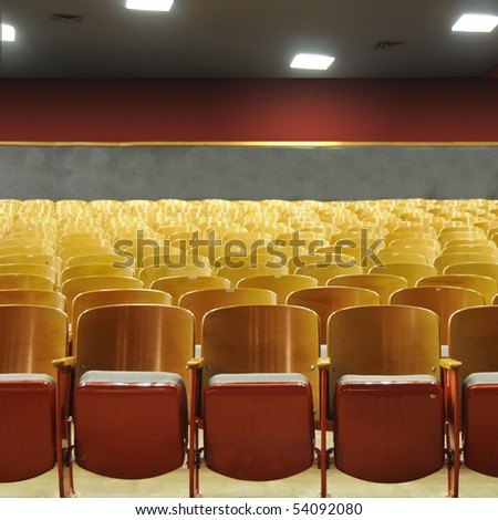 Several rows of theater seats in an auditorium with lights above.