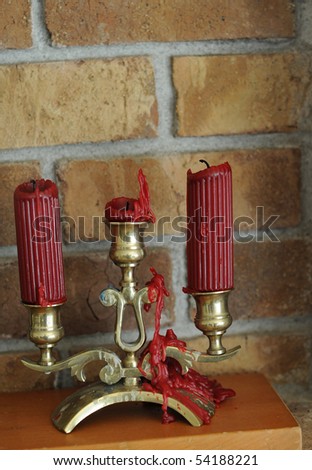 Melted wax candle with red wax dripping down an old golden brass candle holder.