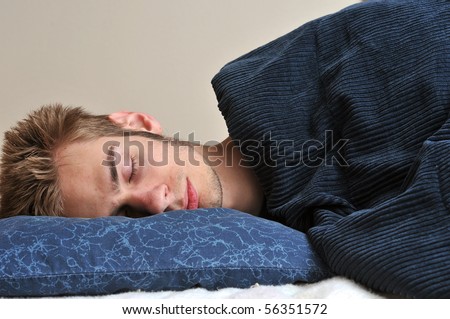 Young Caucasian teenage adult male sleeping on his pillow with his eyes closed.