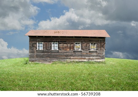An old shack in a big empty green grass field.