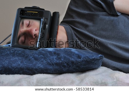 A man with a TV on his head sleeping on his bed, off.
