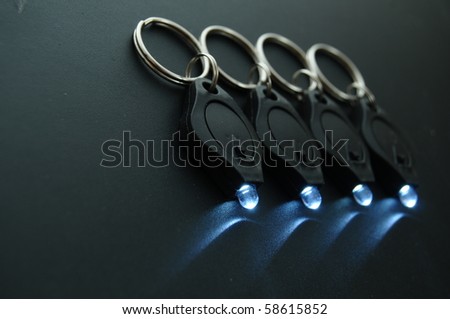 Miniature LED keychain lights on a black surface with shallow depth of field.