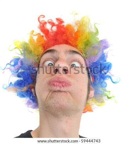 A white Caucasian young adult wearing a silly clown wig with rainbow colorful hair.