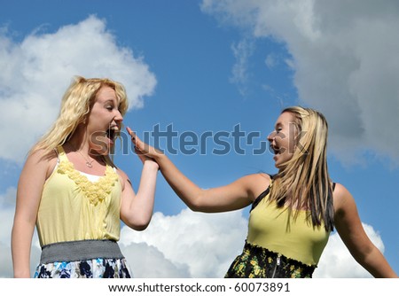 Two young happy girl friends high five each other smiling and laughing.