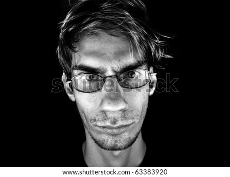 A serious white Caucasian male wearing glasses on a black background with dramatic lighting.