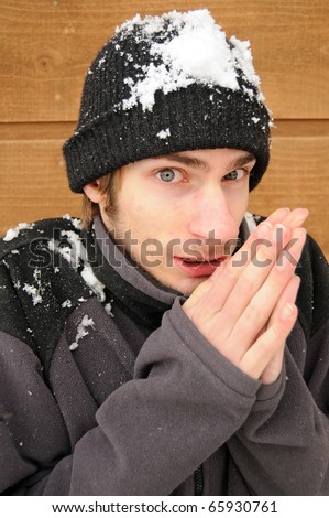 stock photo Young man shivers rubbing his hands together in the snow