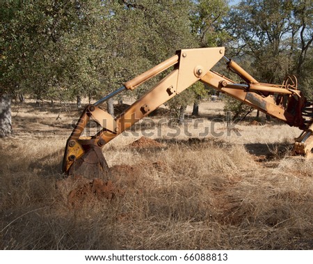 A backhoe digging up some dirt holes in the ground.