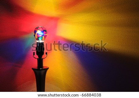 A colorful lightbulb with painted rainbow colors projecting onto the wall behind it with copyspace with room for your text