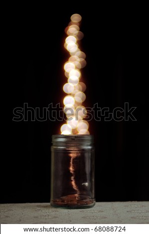 Clear glass jar with magical bokeh dots popping out. Isolated on black background