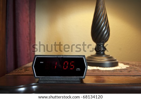 A digital alarm clock displaying 1 pm on the backlit LCD.