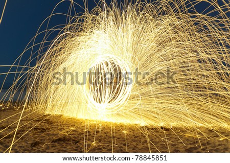 Spinning lit steel wool sparks on the beach at high speed