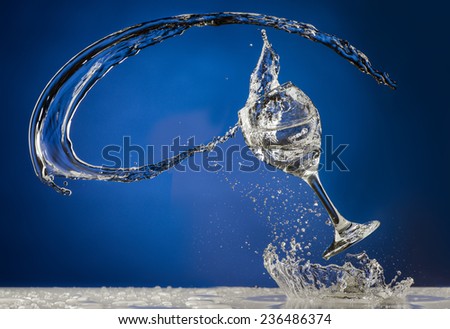 Dramatic Stop Motion Liquid Spilling from Wine Glass on Blue Background