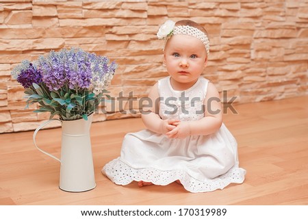 Little girl in white dress with a smart flower on her head smiling and rejoicing / Emotions baby