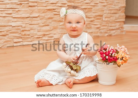 Little girl in white dress with a smart flower on her head smiling and rejoicing / Emotions baby