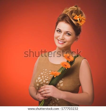 Attractive plus size model. Portrait of beautiful curly young blond woman with flowers in her hair posing on orange.